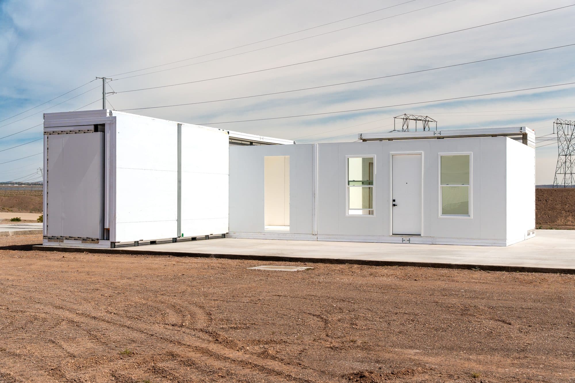 A Boxabl Casita partly unfolded on a concrete foundation, its folding wall panels opening out